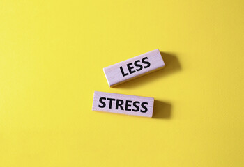 Less stress symbol. Wooden blocks with words Less stress. Beautiful yellow background. Healthcare and Less stress concept. Copy space.