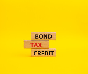 Bond Tax Credit symbol. Concept word Bond Tax Credit on wooden blocks. Beautiful yellow background. Business and Bond Tax Credit concept. Copy space