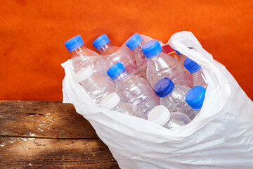 a bag full of plastic bottles to recycle on wood table