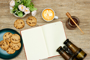 latte art coffee and cookies and honey, empty notebook on notebook with old binocular 