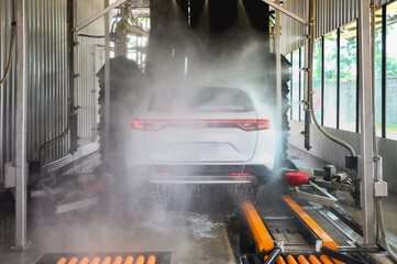 White car going through an automated car wash, automatic high-pressure water spray in the car wash...