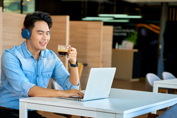Obraz na płótnie Canvas Smart asian male drink a cup of coffee while meeting online with laptop in co working space