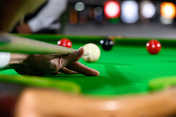 Hand of professional snooker player closeup aiming shot white ball on snooker table. - obrazy, fototapety, plakaty
