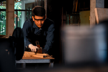 Fototapeta na wymiar Asian carpenter craftsman making pool cue or snooker cue with a manual hand wood planer in carpentry workplace in an old wooden shed. Handmade craftsman concept.