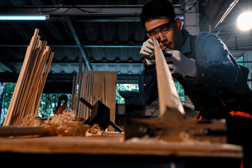 Asian carpenter craftsman check lines of wood while making pool cue or snooker cues with a manual hand wood planer in a carpentry workplace in an old wooden shed. Handmade craftsman concept.