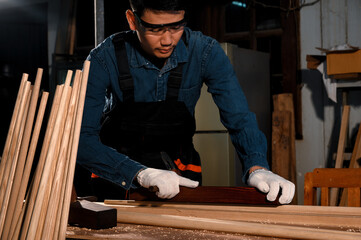 Asian carpenter craftsman making pool cue or snooker cue with a manual hand wood planer in carpentry workplace in an old wooden shed. Handmade craftsman concept.