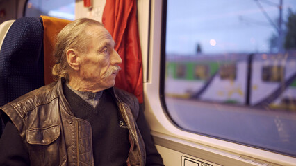 Close up of senior with glasses travels in a train and looks at out the window
