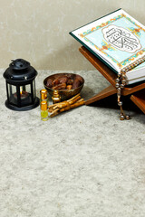 Mawlid al nabi or ramadan, eid concept. lantern with perfume and muslim book with Arabic calligraphy Quran - translation : the noble book of Muslims around the world on stand and dates fruit