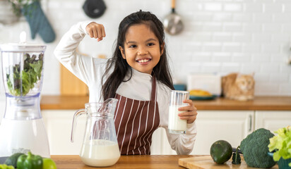 Portrait of enjoy happy little asian child girl smiling having protein breakfast drinking and hold...