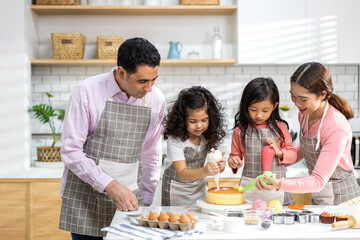 Portrait of enjoy happy love asian family father and mother with little asian girl daughter child play and having fun cooking food together with baking cookie and cake ingredient in kitchen