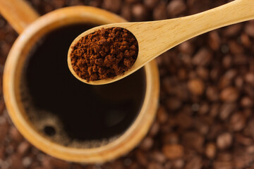 Instant coffee in wooden spoon with wooden cup