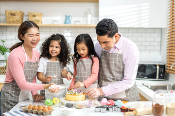 Portrait of enjoy happy love asian family father and mother with little asian girl daughter child play and having fun cooking food together with baking cookie and cake ingredient in kitchen