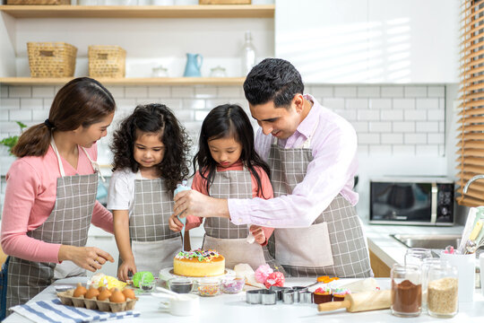 Portrait Of Enjoy Happy Love Asian Family Father And Mother With Little Asian Girl Daughter Child Play And Having Fun Cooking Food Together With Baking Cookie And Cake Ingredient In Kitchen