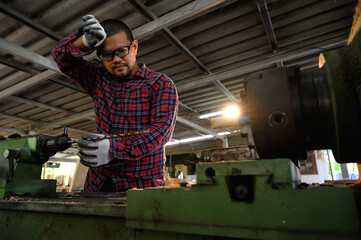 Asian technician working with drilling holes in wood machine in woodwork factory. Concept of skill in working job with machine.