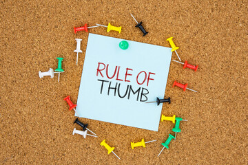 Rule of thumb text on light blue post-it paper pinned on bulletin cork board surrounding by multi...