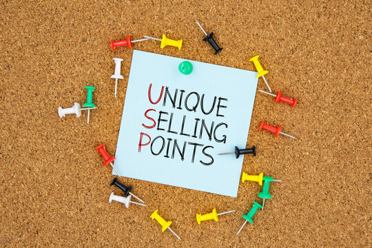 Unique selling points text on light blue post-it paper pinned on bulletin cork board surrounding by multi color pins. This message can be used in business concept about unique selling points.