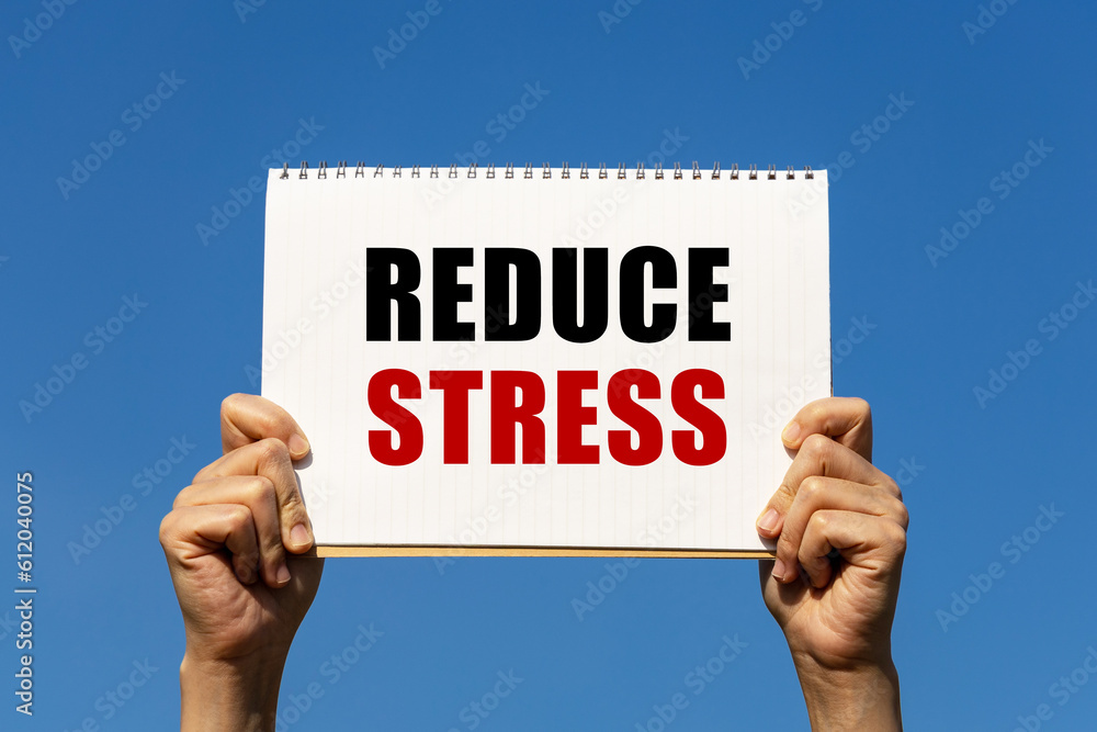 Aufkleber reduce stress text on notebook paper held by 2 hands with isolated blue sky background. this message