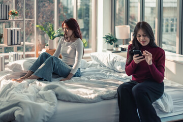 Obraz na płótnie Canvas A Lesbian is annoyed, frustrated because her partner ignores and doesn't pay attention to her. Couples' conflicts make atmosphere tense and stressed. Misunderstanding can destroys relationships.