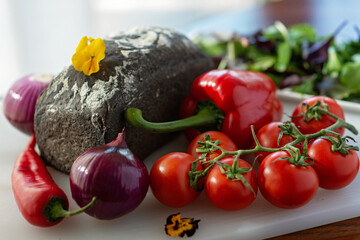 Freshly baked homemade bread with cuttlefish ink, and farm organic vegetables, tomatoes, onions, paprika. Soft selective focus.