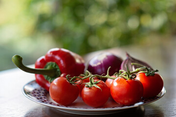 Red tomato, paprika, chili pepper and green onion, farm organic vegetables on a plate. Vegetarian healthy food. Nutritionology. Soft selective focus.