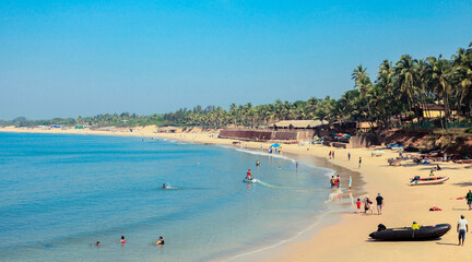 Sunny Beach with Tourists in the Goa state, India - obrazy, fototapety, plakaty