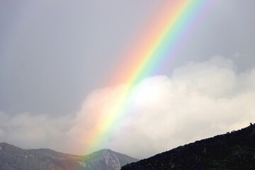 Naklejka na ściany i meble Beautiful rainbow over the mountain and gray sky.