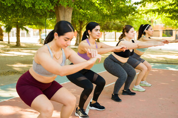 Obraz premium Athletic sporty women doing squat exercises outdoors