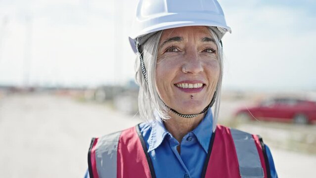 Middle age grey-haired woman builder smiling confident standing at street