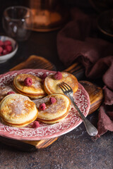 Delicious homemade pancakes with raspberries on vintage plates on a dark background. Close up - 612054006