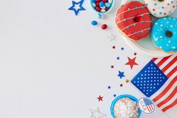 Fototapeta na wymiar Concept of Independence Day with a sweet-filled event. Top view flat lay of american flag, donuts on the plate, muffins, candies, stars on white background with space for text or ad