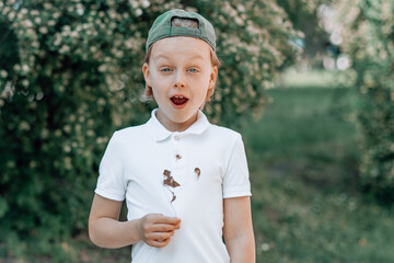 A child showing a chocolate stains  and and cheerfully smiling at the camera on his clothes on a...