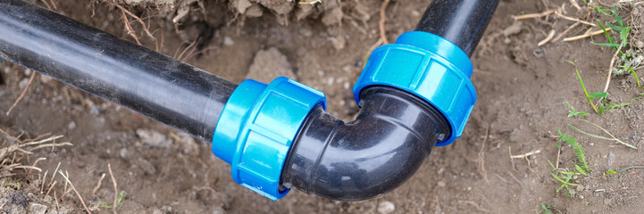 Elbow fitting and black pvc pipes at bend in trench outdoors