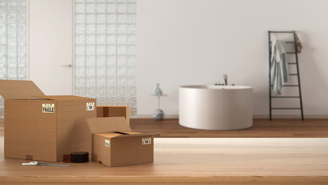Wooden table, desk or shelf with stack of cardboard boxes over blurred view of bathroom with glass brick wall, interior design, moving house concept with copy space