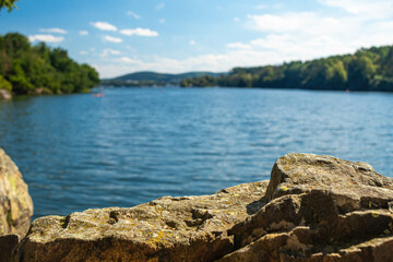 Panorama of a natural body of water with a rock in the foreground in a forest landscape. Brno Reservoir - Czech Republic.