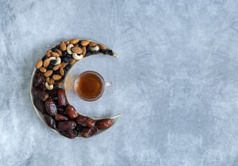Dry fruits and nuts on a crescent moon shape plate with Black tea, Ramadan Iftar background