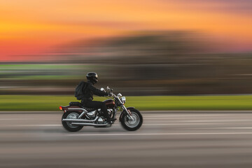 Driving motorcycle with speed blurred background. A speeding motorcycle on an asphalt street....