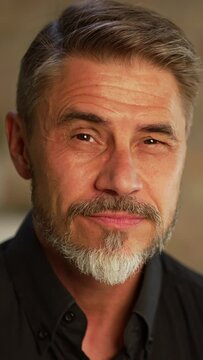Portrait of happy, confident older man at home looking at camera smiling. Mature age, middle age, mid adult casual guy in 50s, bearded, gray hair.