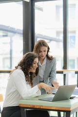 Businesswoman and accountant talking with laptop and tablet Two attractive millennial caucasian businesswoman planning project together at table in office