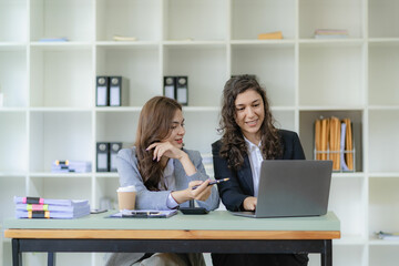 Businesswoman and accountant talking with laptop and tablet Two attractive millennial caucasian businesswoman planning project together at table in office