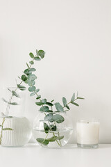 Natural eco home decor with fresh green eucaliptus leaves and trendy soy cube bubble candle. A trendy soy cube bubble candle on white table. Hygge home decoration concept and aromatherapy.