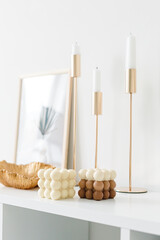 A trendy soy cube bubble candle on white table. Bubble candle on the background of a textured wall. Soy wax candle on a textured table. Interior decor with a handmade candle. 
Hygge home.