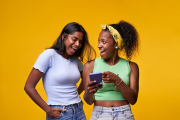 Photo of couple of young student girls happily surprised pointing and looking at cell phone posing...