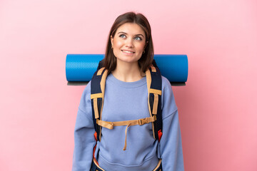 Young mountaineer woman with a big backpack isolated on pink background thinking an idea while looking up