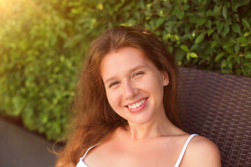 Portrait of happy beautiful young woman at sunny summer day smile and look at camera relax on natural background