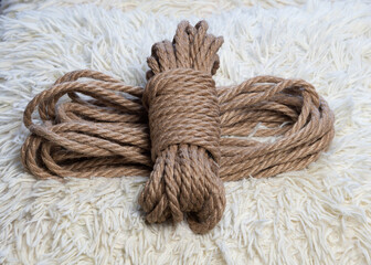 A coil of jute rope for shibari practice on a fleecy white background. Shibari. Concept of BDSM.	