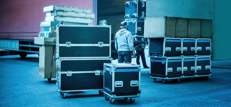 Loading And Unloading Of Concert Equipment. Loading Equipment In A Van. Man Controls The Loading Of Equipment Cases.