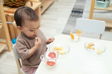 Toddler eating snacks by table