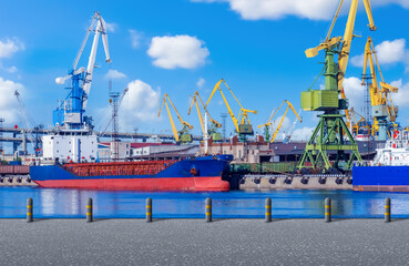 Seaport in sunny weather. Ships in process of unloading. Cranes in harbor. Equipment for unloading...