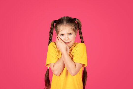 Unhappy preteen girl suffering from tooth ache, tpuching her cheek