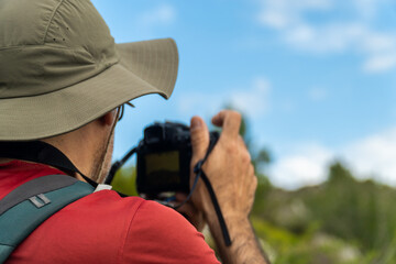 artial view of a man with a hat taking photos with a DSLR camera to nature.